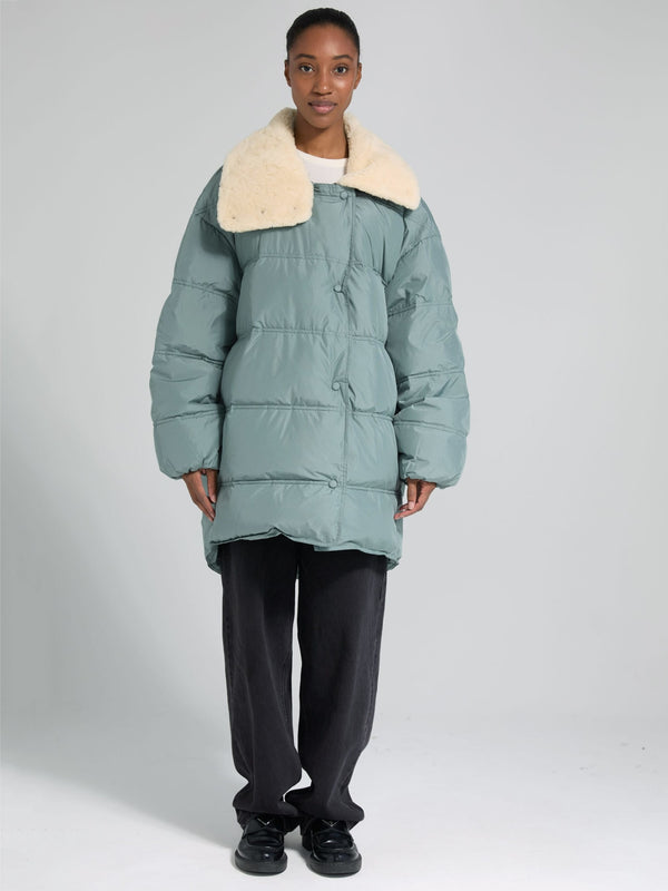 A model wears a cozy, oversized teal puffer jacket with a plush cream collar, showcasing MEOTINE's stylish winter outerwear.