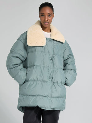 Cozy oversized puffer jacket in soft green with a plush cream collar, perfect for stylish warmth this season by MEOTINE.