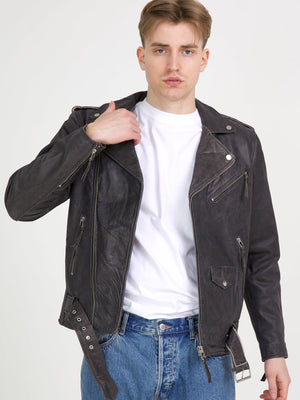 A model wearing a stylish black leather biker jacket from MEOTINE, paired with a white t-shirt and blue jeans.