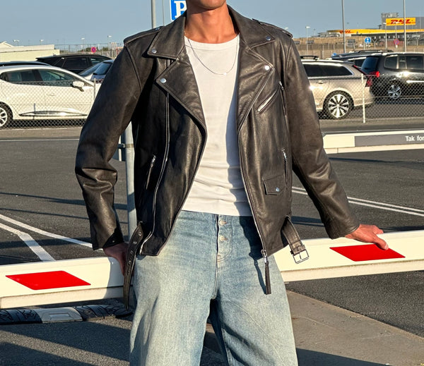 Stylish black leather jacket with a modern fit, paired with light blue jeans, showcasing a casual yet edgy look by MEOTINE.