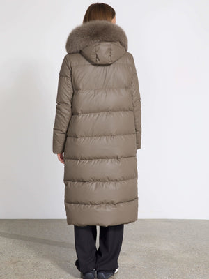 A woman in a long, taupe puffer coat with a fur-lined hood, showcasing the stylish and warm design by MEOTINE.