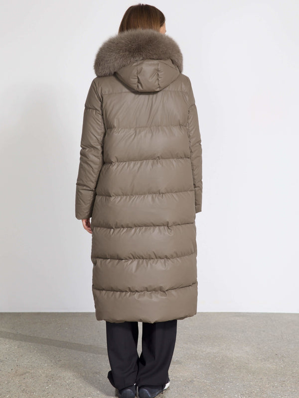 A woman in a long, taupe puffer coat with a fur-lined hood, showcasing the stylish and warm design by MEOTINE.