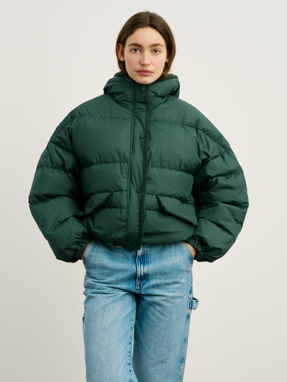 A model wears a stylish green puffer jacket with a cozy collar, paired with light blue jeans, showcasing MEOTINE's trendy design.