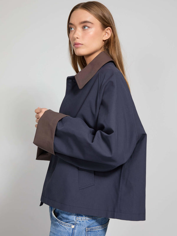 A model showcases a stylish navy jacket with brown oversized cuffs, embodying modern elegance by MEOTINE.