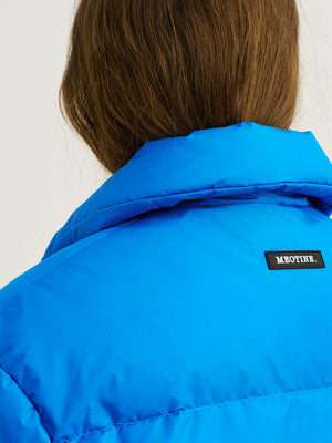 A close-up of a woman's back wearing a vibrant blue jacket with the MEOTINE logo on the collar, showcasing its stylish design.