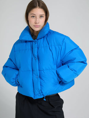 A model showcases a vibrant blue puffer jacket with a high collar and button closure, perfect for stylish warmth by MEOTINE.