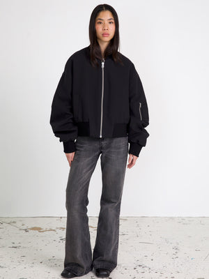 A model wears a stylish black bomber jacket with oversized sleeves, paired with flared jeans, showcasing MEOTINE's modern aesthetic.