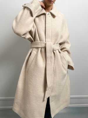A model showcases a cozy, oversized beige coat with a belted waist, perfect for stylish warmth this season by MEOTINE.
