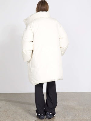 A model wearing a large, cream-colored puffer coat from MEOTINE, styled with black pants, showcasing a cozy, oversized fit.