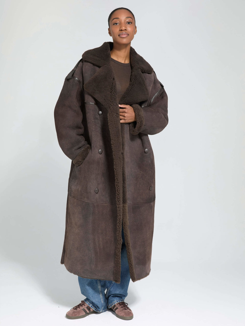A model showcases a stylish brown shearling coat with a cozy collar, paired with a simple top and jeans, by MEOTINE.