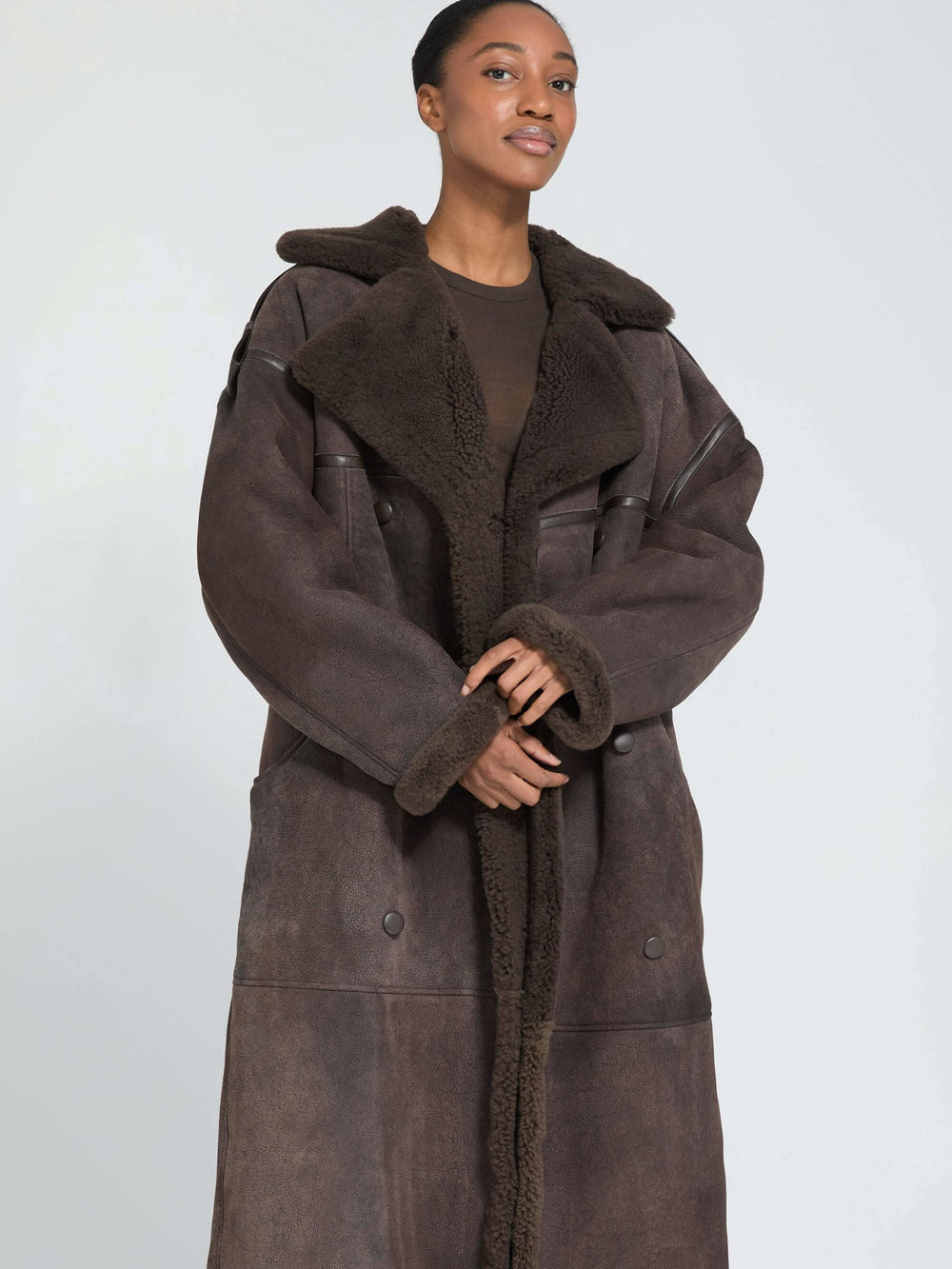 A model showcases a stylish brown shearling coat with a cozy collar, paired with a simple top and jeans, by MEOTINE.