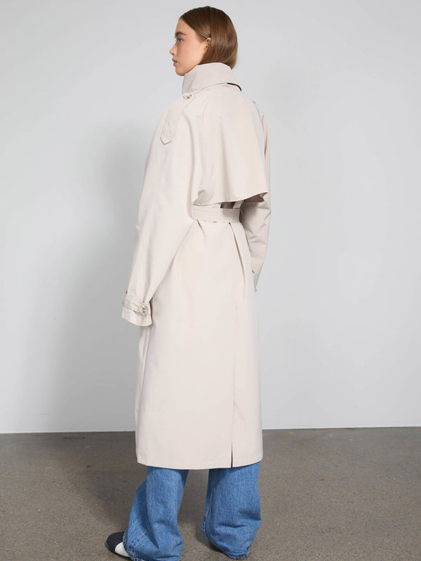 A model wearing a light beige trench coat with a unique back design, paired with blue wide-leg jeans, showcasing MEOTINE's style.