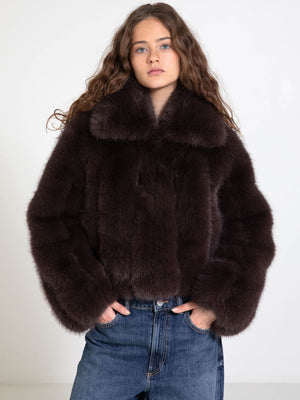 A model wears a luxurious dark brown fur coat with a high collar, paired with casual blue jeans, showcasing MEOTINE's elegant style.