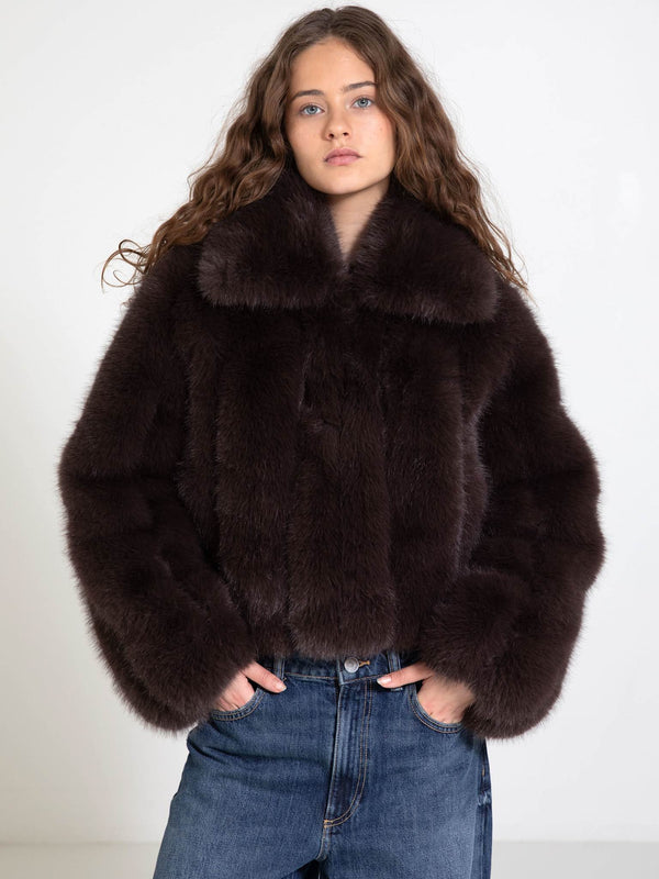 A model wears a luxurious dark brown fur coat with a high collar, paired with casual blue jeans, showcasing MEOTINE's elegant style.