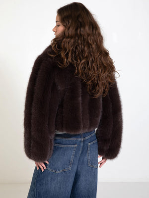 A model showcases a dark brown faux fur jacket from MEOTINE, paired with wide-leg denim jeans, highlighting a stylish back view.