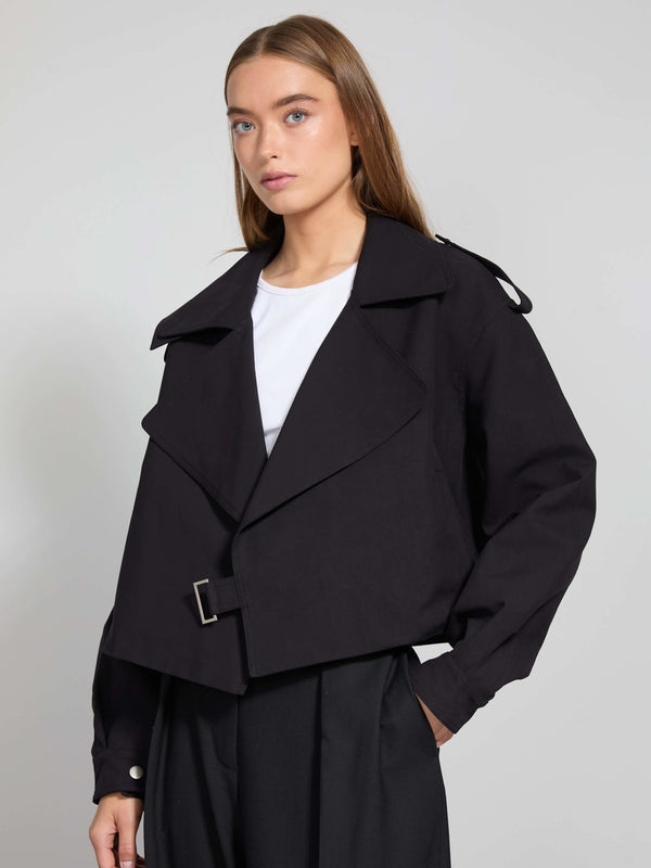 Stylish black cropped jacket with a belted waist and wide lapels, paired with a simple white top, showcasing MEOTINE's modern design.