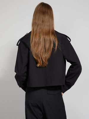 A model showcases a stylish black cropped jacket with shoulder details, paired with sleek black trousers, by MEOTINE.