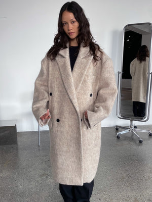 A model showcases a cozy, oversized beige coat with a double-breasted design, embodying MEOTINE's chic style.