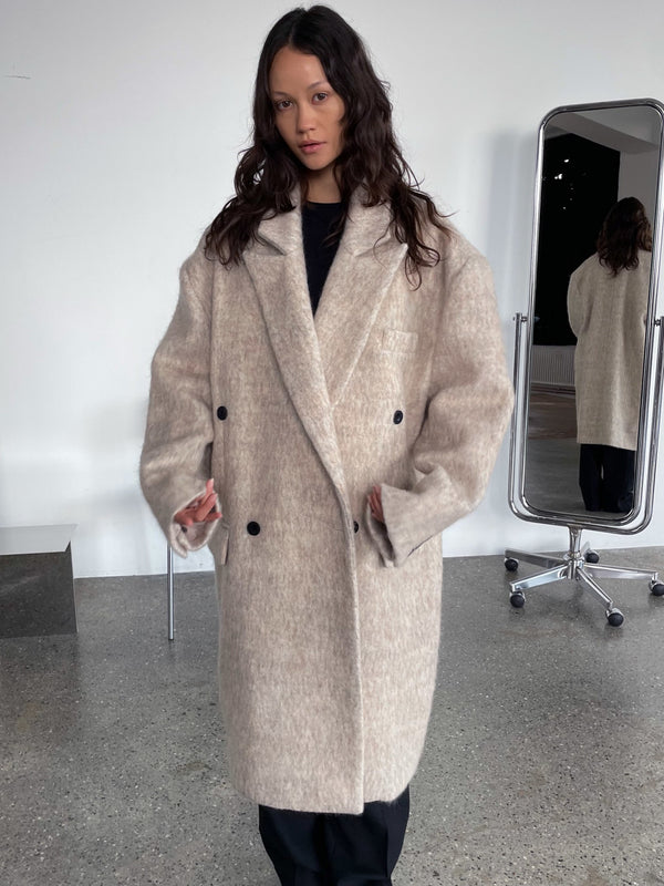 A model showcases a cozy, oversized beige coat with a double-breasted design, embodying MEOTINE's chic style.
