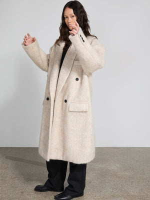 A model showcases a cozy, oversized beige coat with a textured finish, featuring a double-breasted design by MEOTINE.