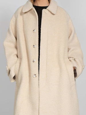 Cozy cream-colored oversized coat with a button-up front and side pockets, perfect for chilly days. By MEOTINE.