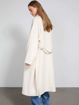 A model showcases a cozy, cream-colored MEOTINE robe with a tie waist, styled with loose blue jeans, highlighting a relaxed look.