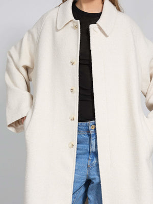 Cozy cream oversized coat with a button-up front, featuring side pockets, perfect for layering in cooler weather by MEOTINE.
