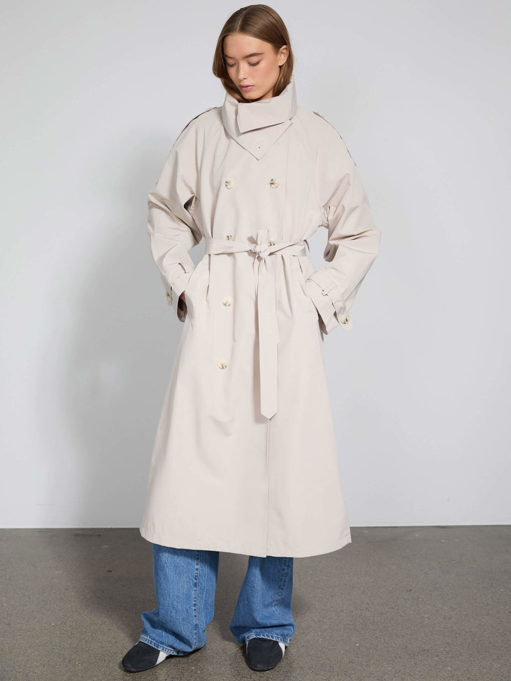 A model showcases a stylish beige trench coat with a belted waist and high collar, embodying MEOTINE's modern elegance.