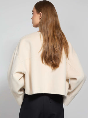 A model showcases a cozy, cream-colored cropped sweater with a relaxed fit, perfect for layering. MEOTINE offers stylish comfort.