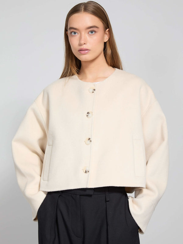 A model wears a cream-colored cropped jacket with large buttons and side pockets, showcasing MEOTINE's stylish design.