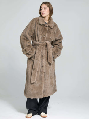 A model wears a cozy, oversized brown faux fur coat with a belt, showcasing a stylish and warm look by MEOTINE.