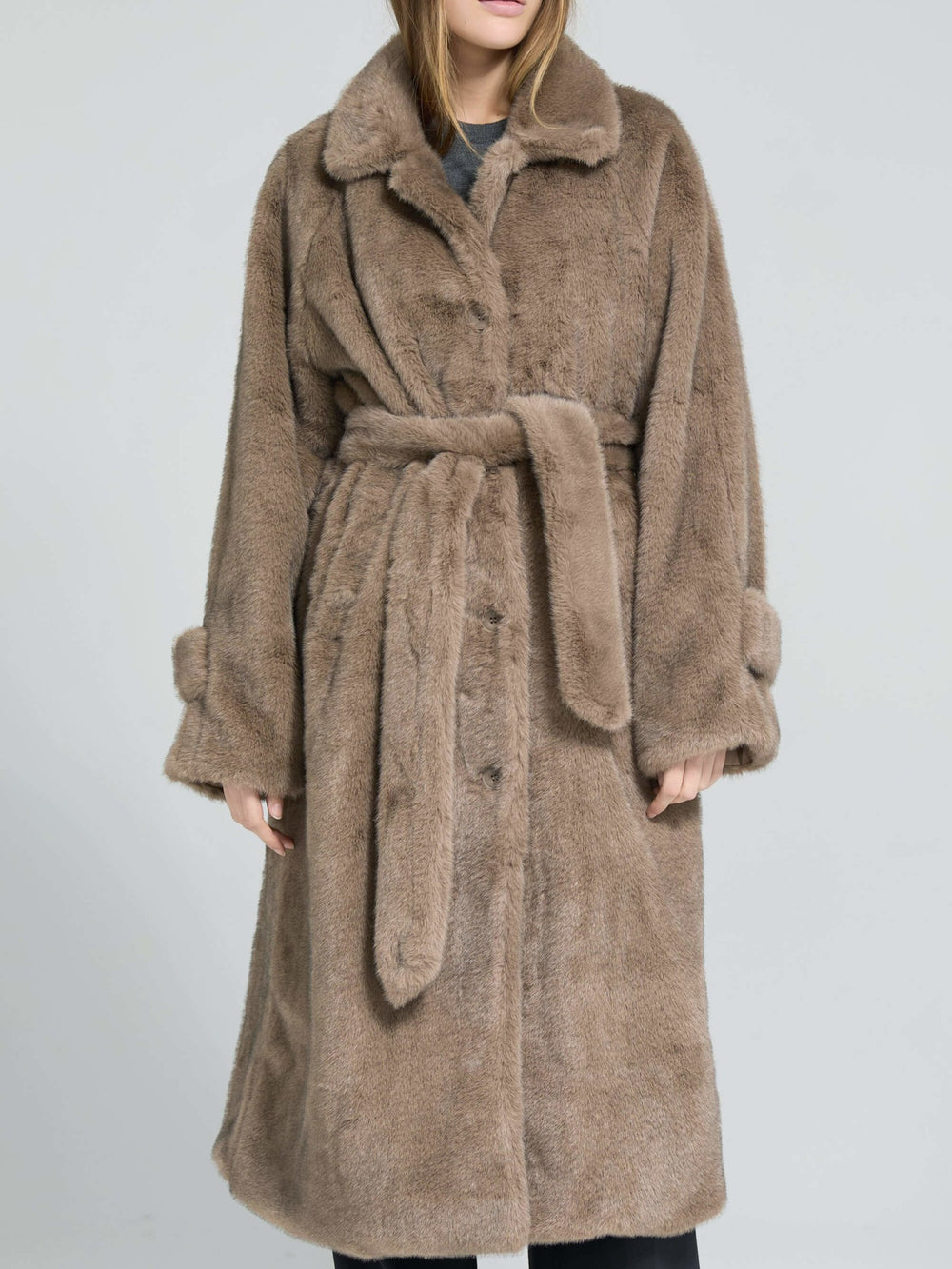 A model wears a cozy, oversized brown faux fur coat with a belt, showcasing a stylish and warm look by MEOTINE.
