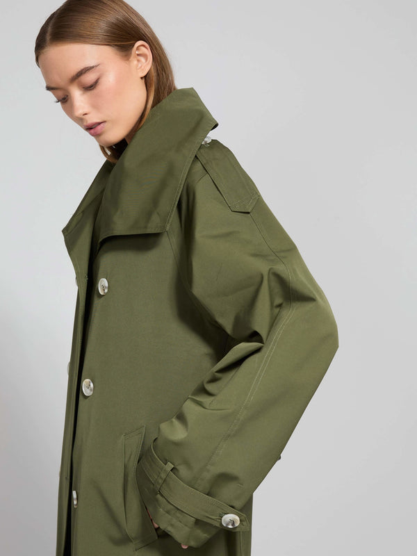 A model showcases a stylish olive green trench coat with a high collar and large buttons, embodying MEOTINE's modern aesthetic.
