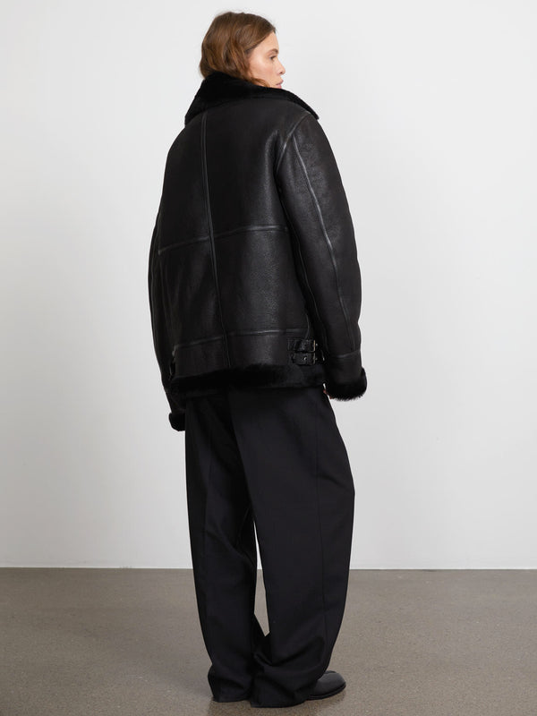 A model showcases a black leather jacket with fur trim, paired with loose black trousers, embodying MEOTINE's chic style.