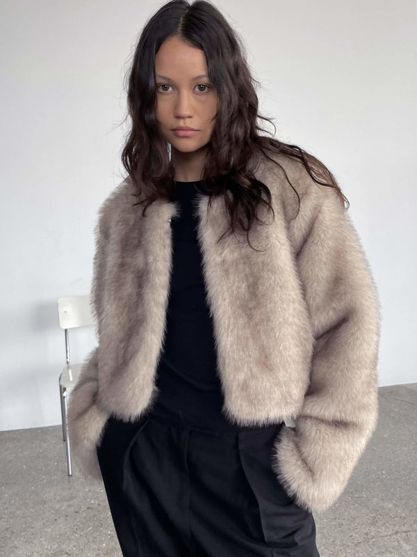A model wearing a soft, beige faux fur jacket over a black top, exuding a chic and cozy vibe, showcasing MEOTINE's stylish design.