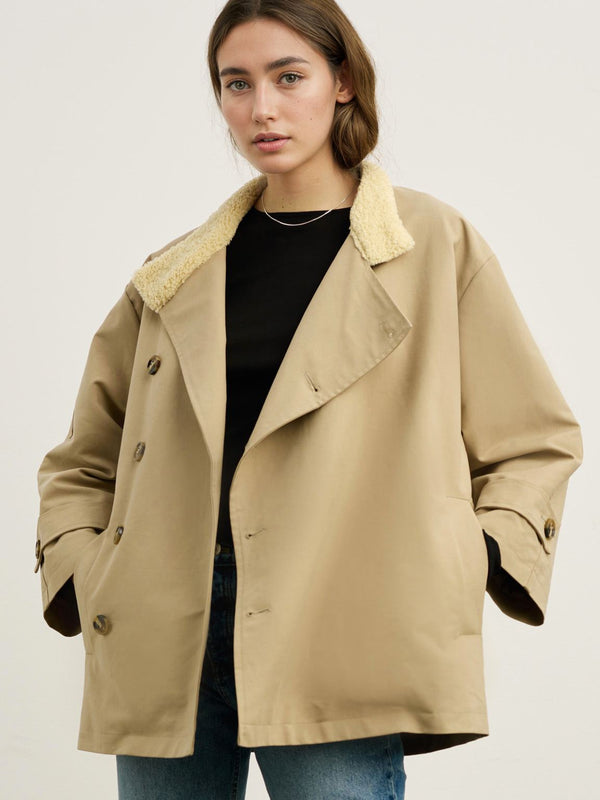 A model wears a stylish beige oversized coat with a soft collar, paired with a black top and blue jeans, showcasing MEOTINE's chic design.