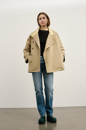 A model wears a beige oversized coat with a soft collar, paired with blue jeans and green clogs, showcasing MEOTINE's stylish design.