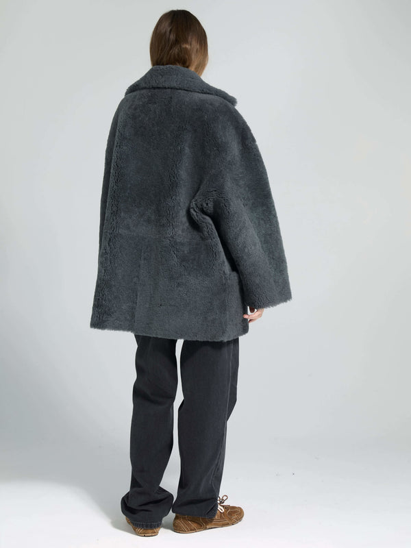 Cozy gray oversized coat with a plush texture, styled with loose black trousers, perfect for a chic winter look by MEOTINE.