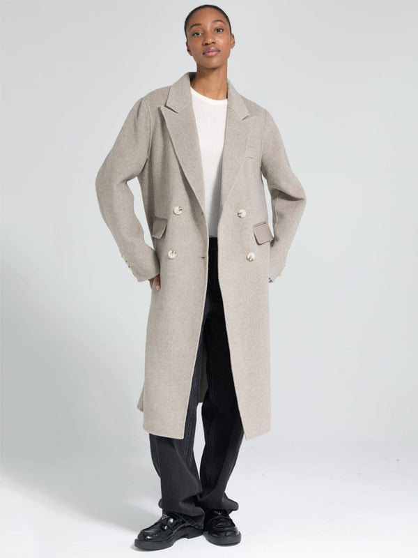 A model showcases a stylish beige double-breasted coat by MEOTINE, paired with a simple white top and black trousers.