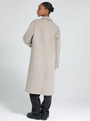 A model showcases a stylish beige coat from MEOTINE, featuring a sleek design and a relaxed fit, perfect for any occasion.