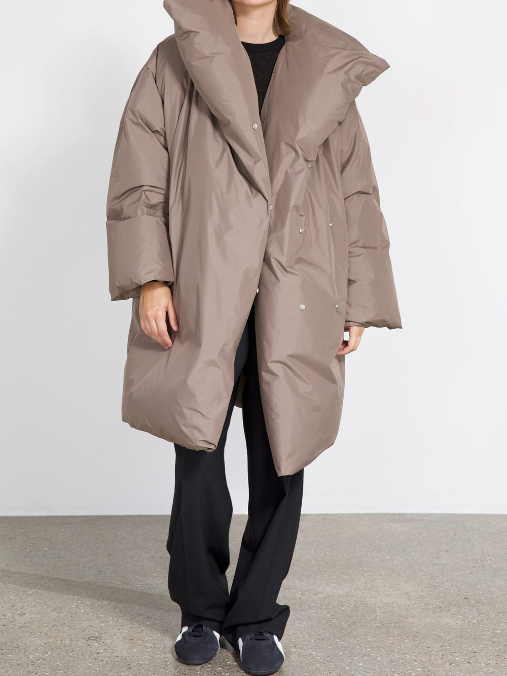 Oversized taupe puffer coat with a dramatic collar, styled with black pants and shoes, showcasing MEOTINE's modern design.