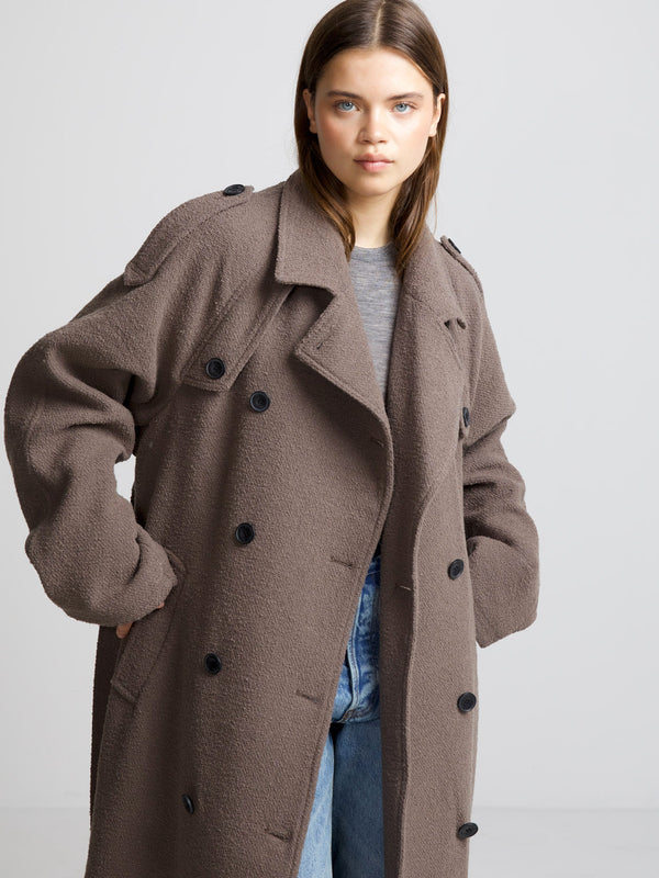 A model showcases a cozy, oversized brown coat with large buttons, paired with a casual gray top and denim jeans, by MEOTINE.
