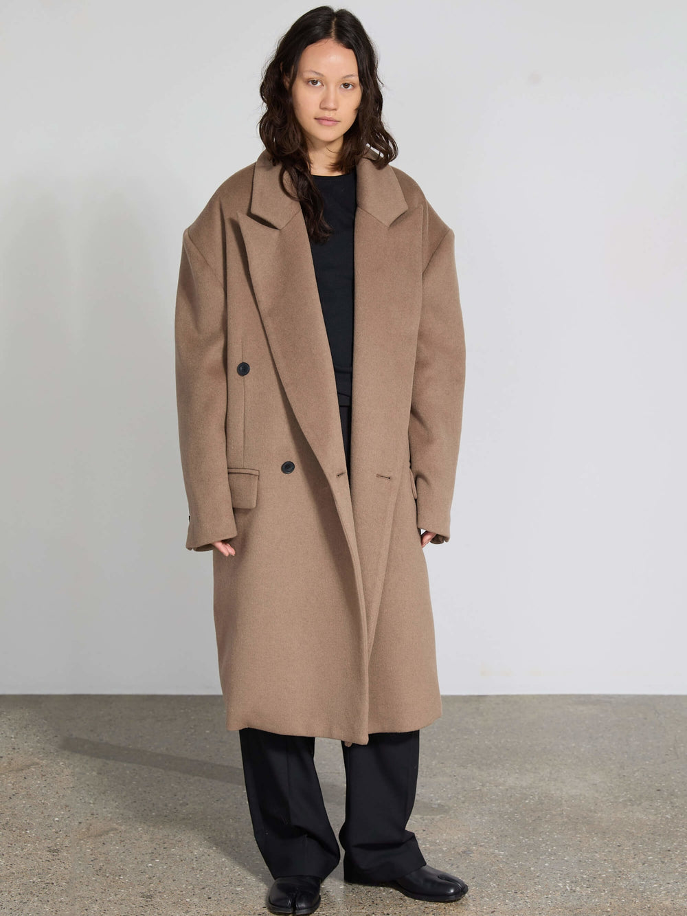 A model showcases a stylish oversized brown coat with a tailored fit, featuring large buttons and a chic collar, by MEOTINE.