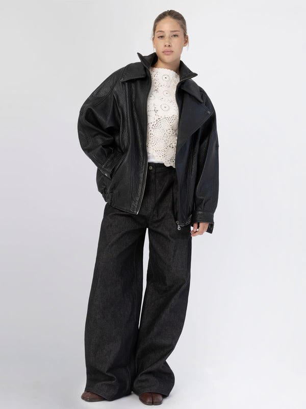 A model wears a stylish oversized black leather jacket paired with wide-leg dark pants, showcasing MEOTINE's contemporary fashion.