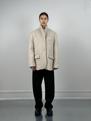 A model showcases a stylish, oversized beige coat with a textured finish, paired with black trousers, representing MEOTINE's chic aesthetic.