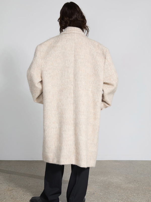 A person wearing a soft, beige MEOTINE coat, viewed from the back, showcasing its oversized fit and cozy texture.