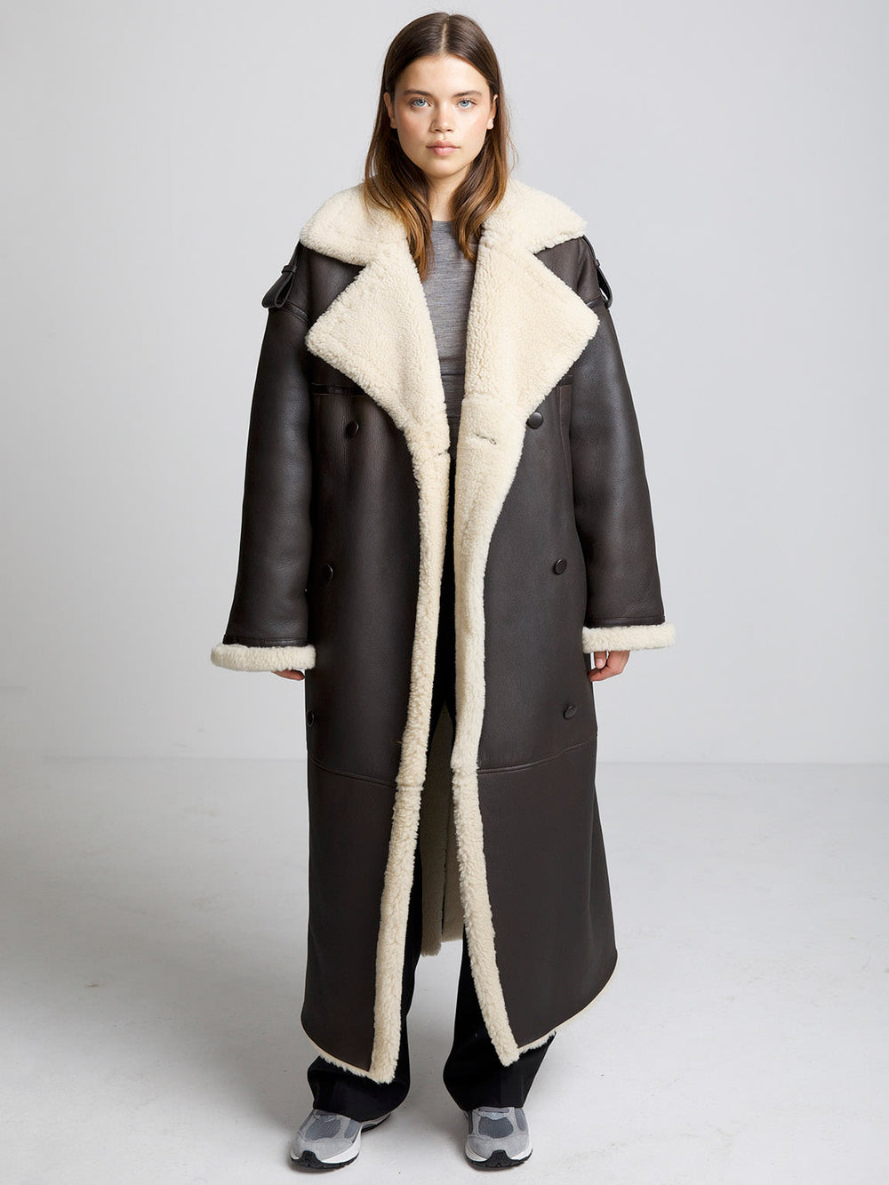 A model showcases a stylish brown shearling coat with a cozy cream lining, perfect for a chic winter look by MEOTINE.