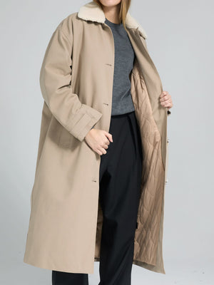 A woman models a beige MEOTINE coat with a soft collar, showcasing its stylish interior and relaxed fit over a gray top.