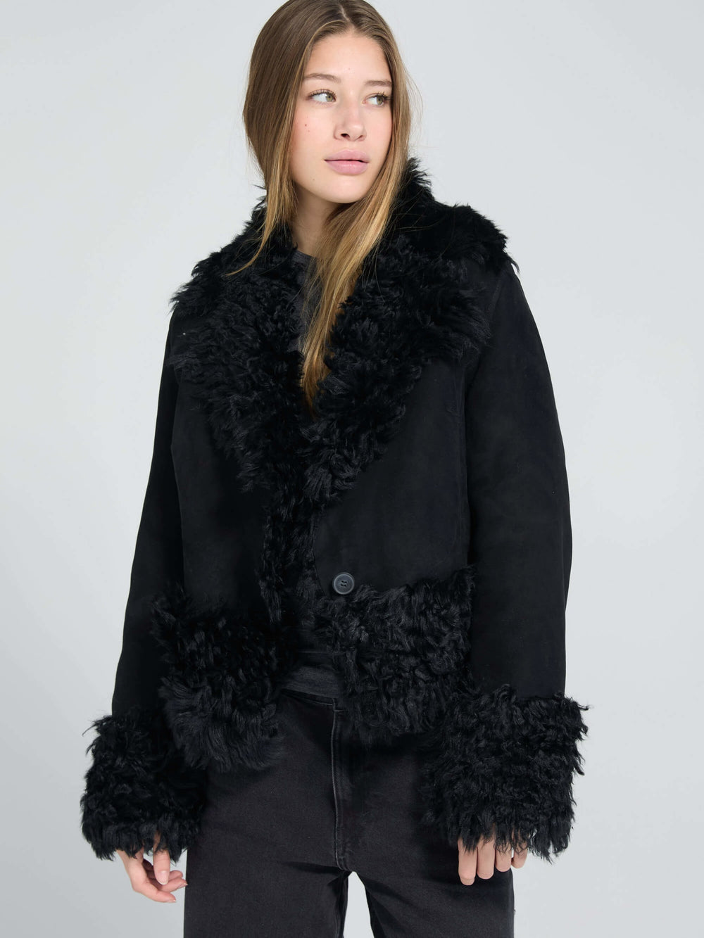 Stylish black jacket with fluffy fur trim and a button closure, perfect for a chic look. Designed by MEOTINE.