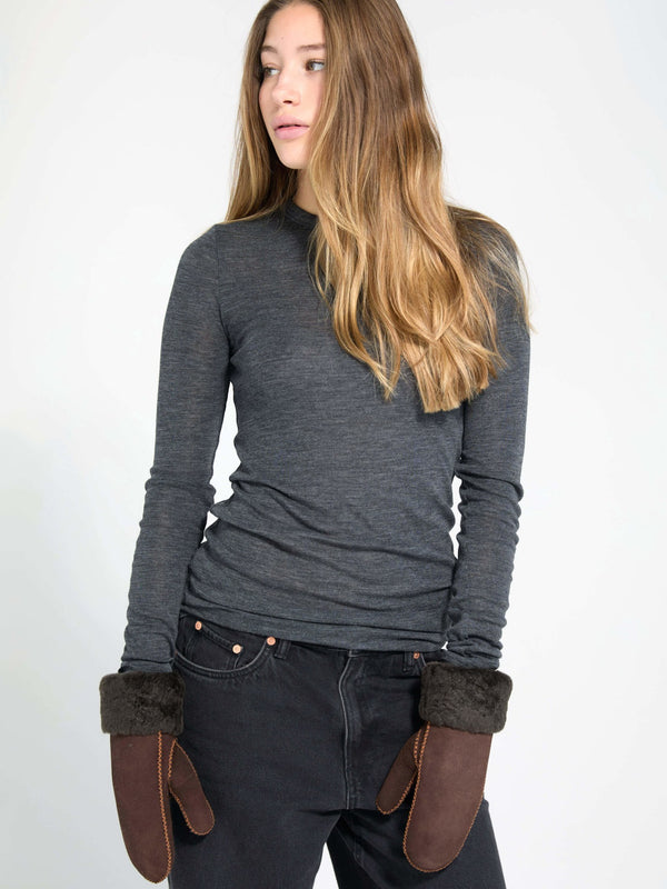 Stylish model wearing brown MEOTINE mittens with fur cuffs, paired with a fitted gray long-sleeve top and black jeans.